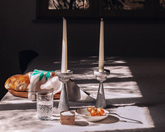 Dining table setting with bread, glass, and plate in a dimly lit room.